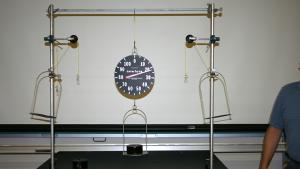 Force scale holding a 2 kg mass. The force scale reads 20 N.