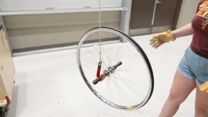 Spinning bicycle wheel with axle on hook